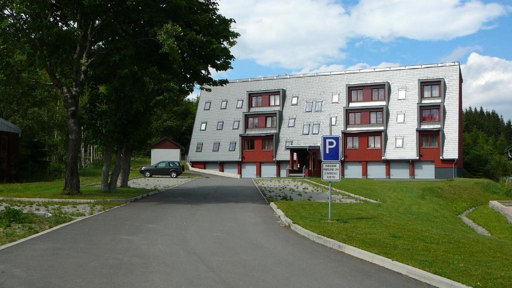 um grande edifício branco com uma placa de estacionamento em frente em Apartmány Racek em Ostružná