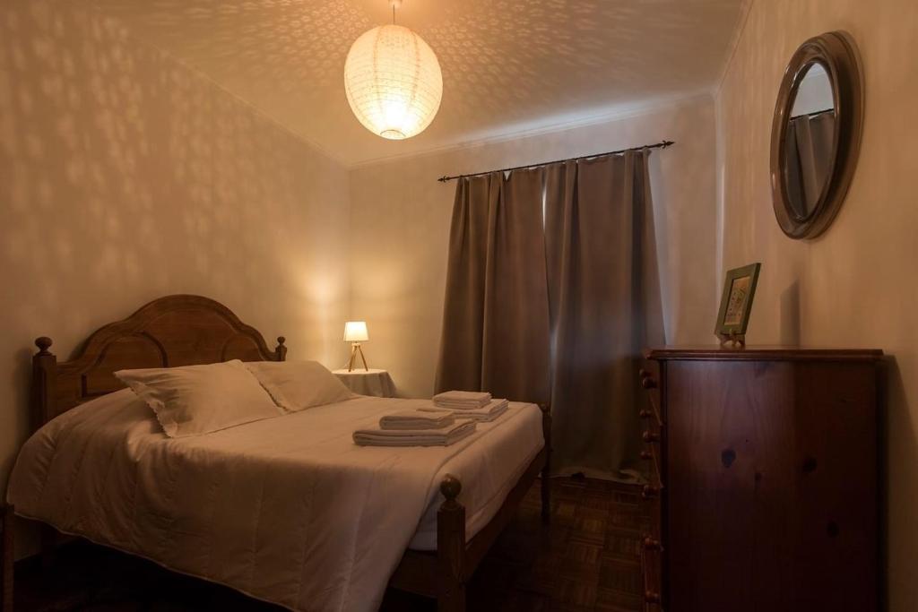 a bedroom with a bed and a lamp and a mirror at Casa Caió in Ribeira Grande