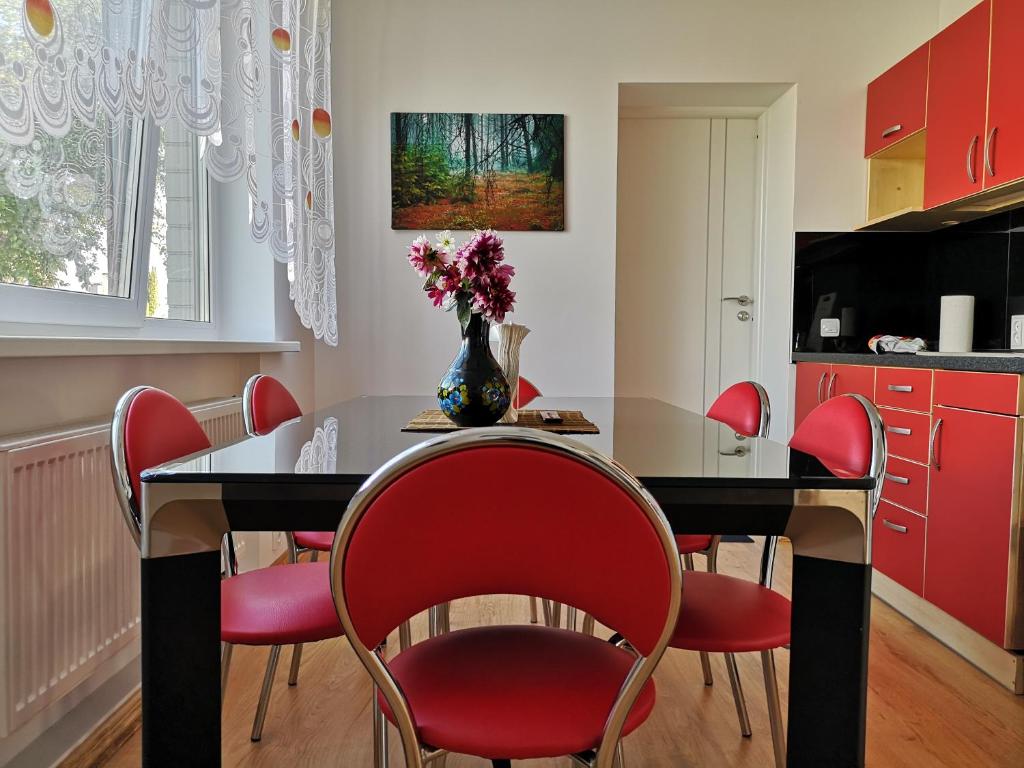 a kitchen with a dining room table with red chairs at Vorutos Terasa in Anykščiai