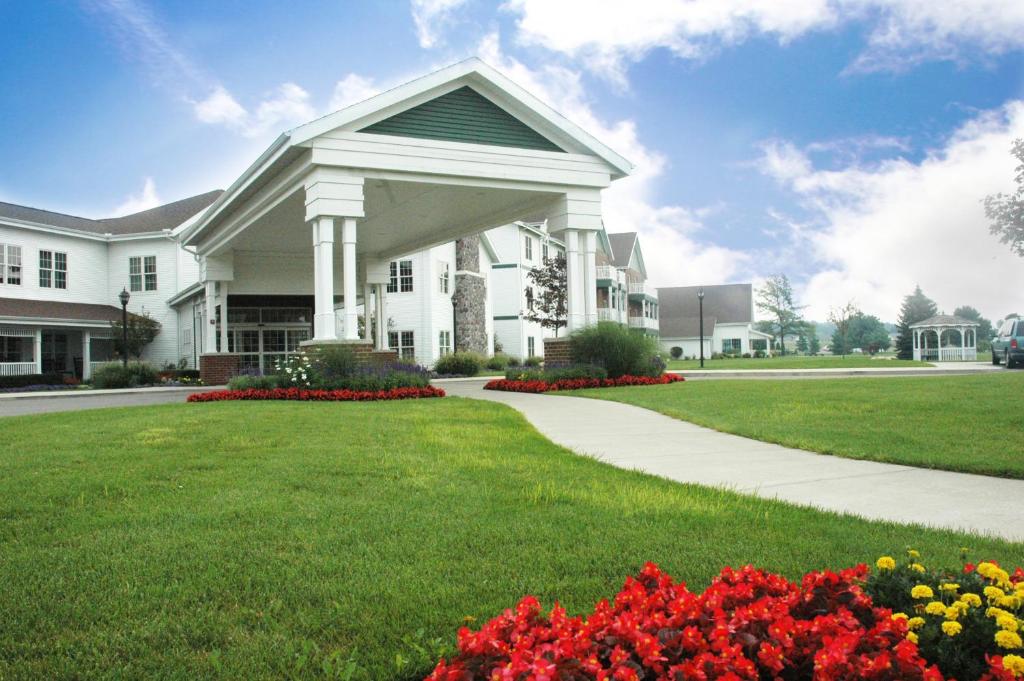 Une grande maison blanche avec des fleurs dans la cour dans l'établissement Essenhaus Inn & Conf. Center, à Middlebury