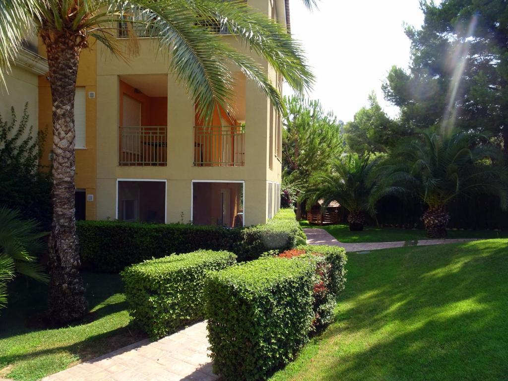 a building with trees and bushes in front of a yard at Cortes valencianas 45 in Náquera