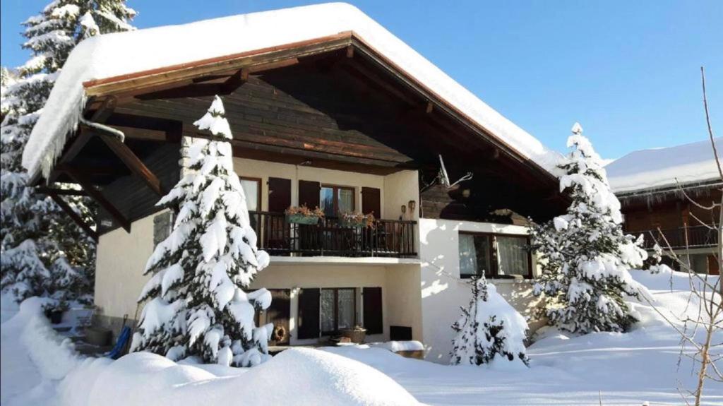 une maison recouverte de neige avec un balcon dans l'établissement Résidence Chalet La Barallette - Esc'Appart, au Grand-Bornand