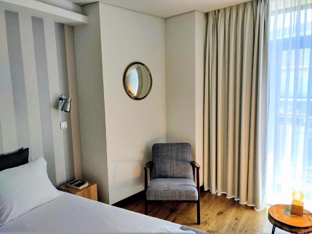a bedroom with a bed and a chair and a mirror at PicPorto Apartment in Porto