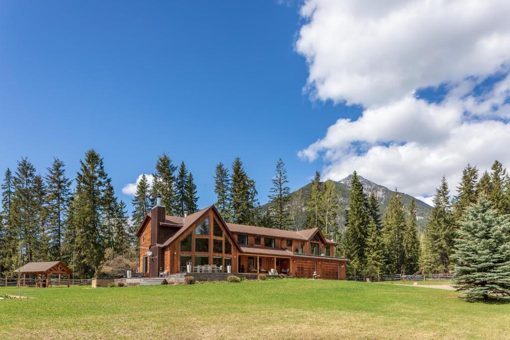 a large wooden house in a field with trees at Home Lodge in Golden