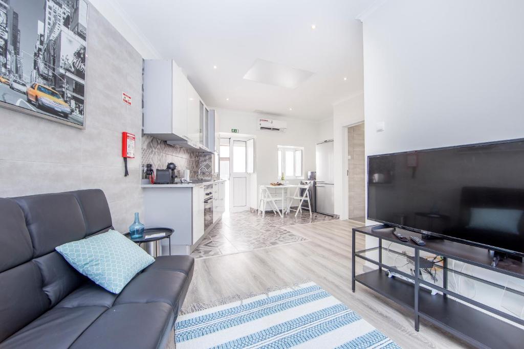 a living room with a couch and a flat screen tv at FishermenApartments - Casa do Espargal in Paço de Arcos