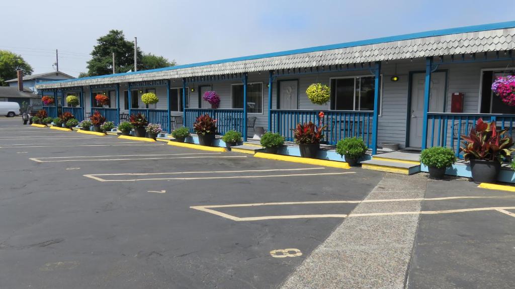 a parking lot with a blue building with potted plants at Mermaid Inn in Long Beach