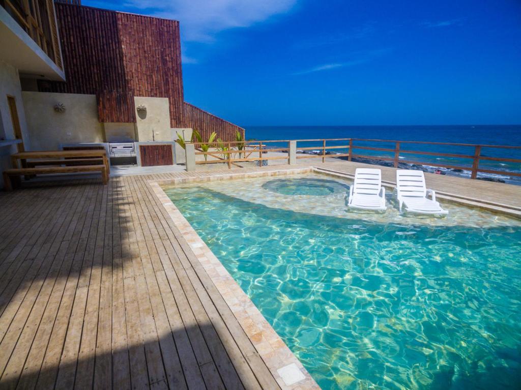 a swimming pool with two chairs and the ocean at Canoas Lofts in Canoas De Punta Sal