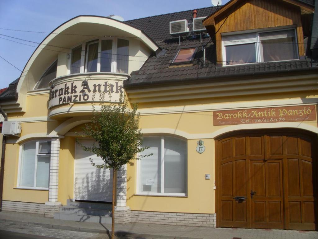 a large yellow building with a wooden garage at Barokk Antik Guest Hause in Kecskemét