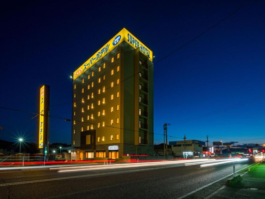 ein Hotelgebäude mit Neonschild darüber in der Unterkunft Super Hotel Fukushima Iwaki in Iwaki