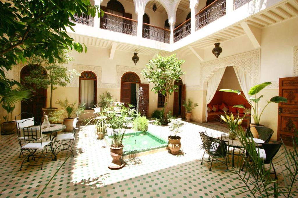 un patio con piscina y muchas plantas en Riad Massiba, en Marrakech