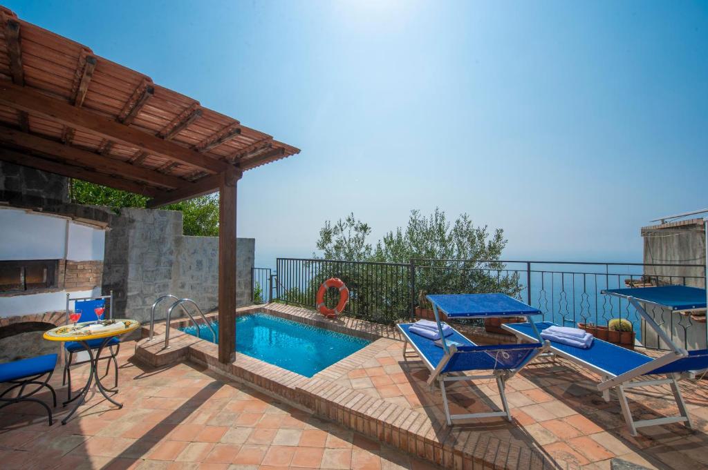 a patio with a swimming pool with chairs and a table at Casa Mare in Praiano