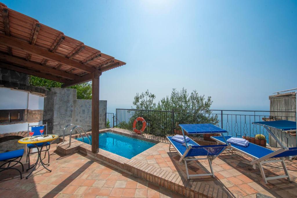 un patio con piscina, sedie e tavolo di Casa Mare a Praiano