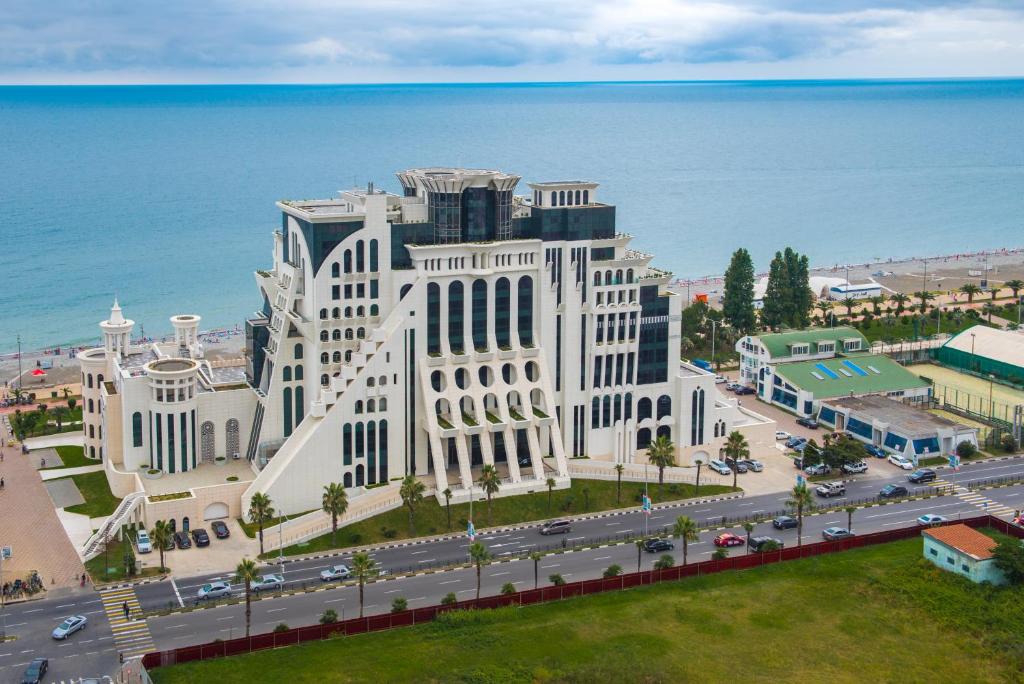a large white building next to the ocean at The Grand Gloria Hotel in Batumi