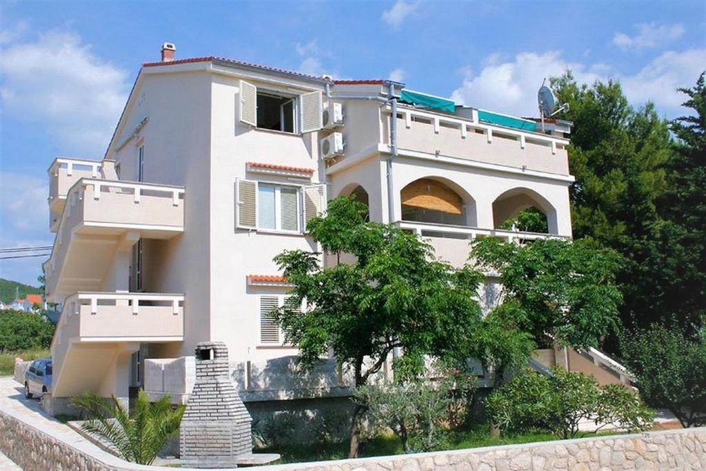 a white building with a tree in front of it at Apartments Vrtlici in Stara Novalja