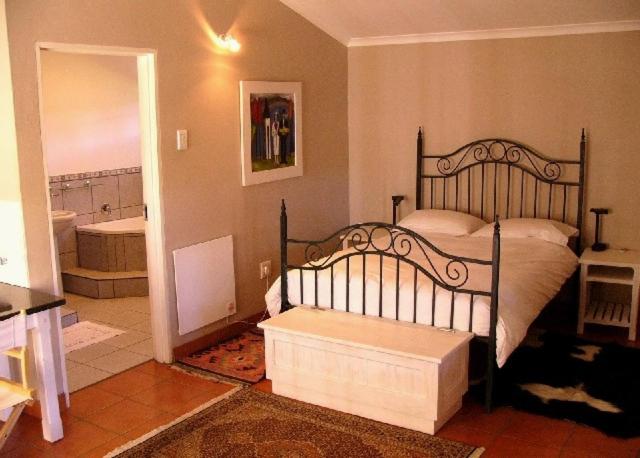 1 Schlafzimmer mit einem Bett und einem Bad in der Unterkunft Rose Garden Manor House in Harrismith