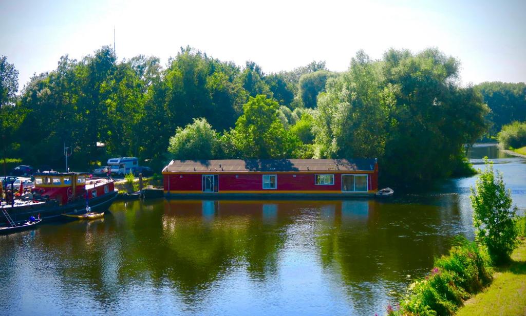 ein Hausboot auf einem Fluss mit Bäumen im Hintergrund in der Unterkunft B&B De Leeuw in Zwolle