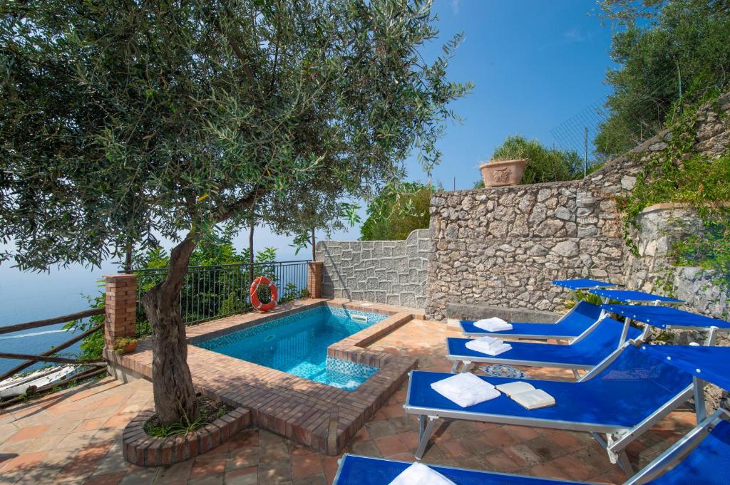 una piscina con sedie blu e un albero di Villa Tranquillita a Praiano