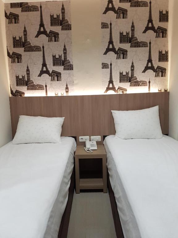 two beds in a room with a table between them at Ethan Hotel Kelapa Gading in Jakarta