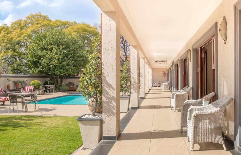 a porch of a house with chairs and a pool at Inn and Out Plus Craighall in Johannesburg