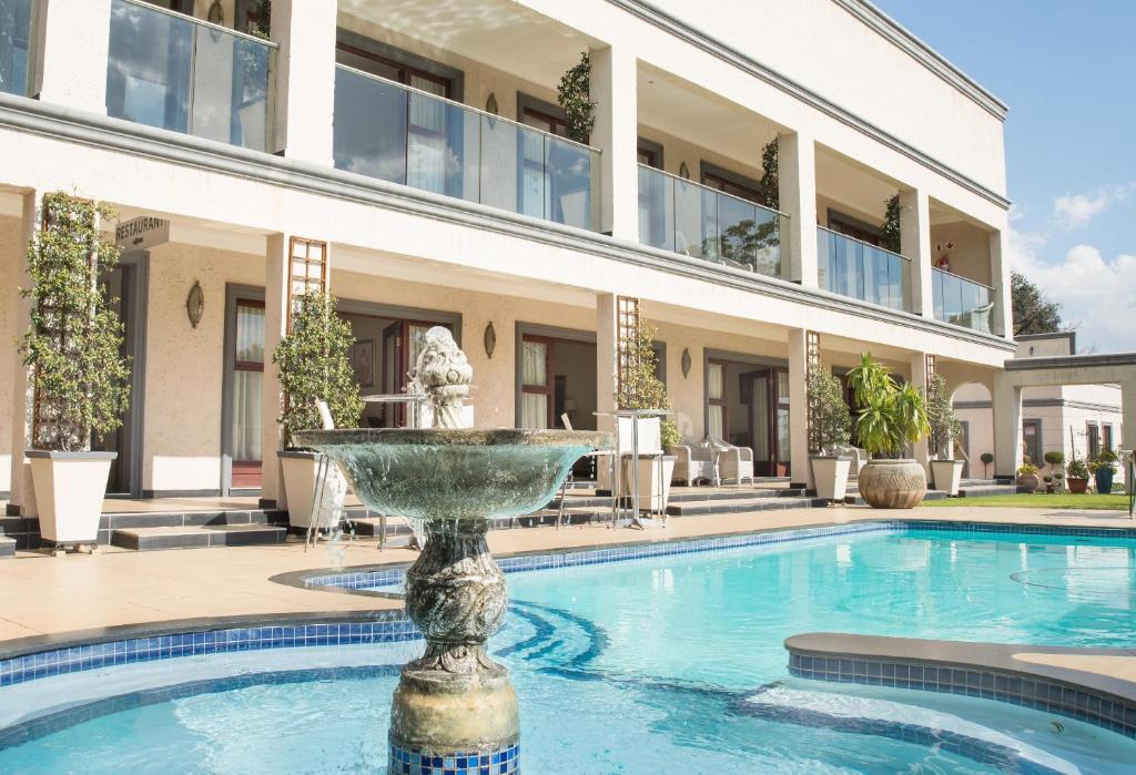 a swimming pool with a fountain in front of a building at Gardenia Boutique Hotel in Johannesburg