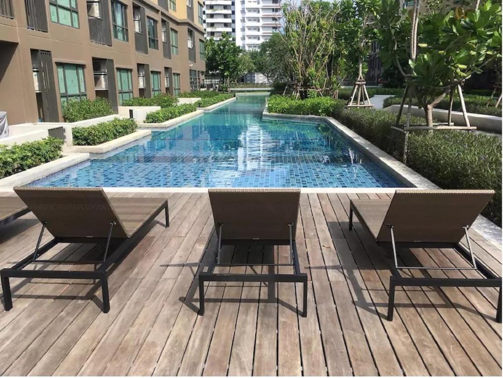 a swimming pool with two chairs on a wooden deck at Rain Cha Am Hua Hin in Phetchaburi