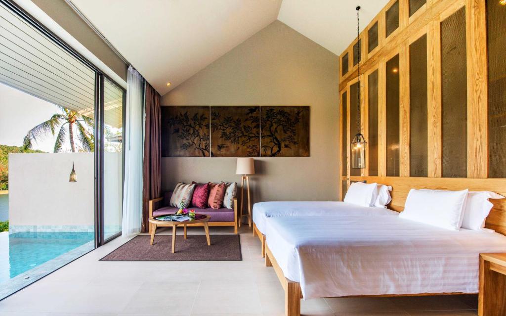 a bedroom with a bed and a couch and a window at Sunsuri Phuket - SHA Plus in Nai Harn Beach