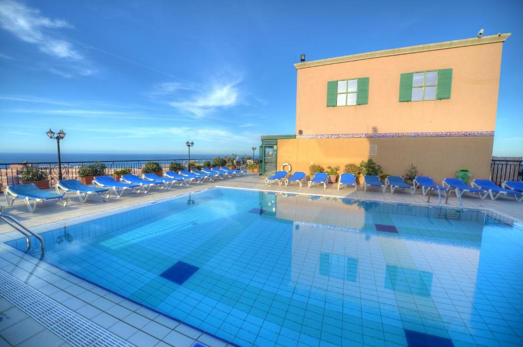 a swimming pool with chairs and a building at Vivaldi Hotel in St. Julianʼs