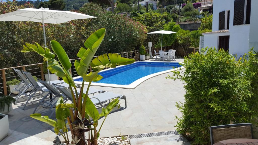 una piscina con sillas y sombrilla en Villa Corazón en Capdepera
