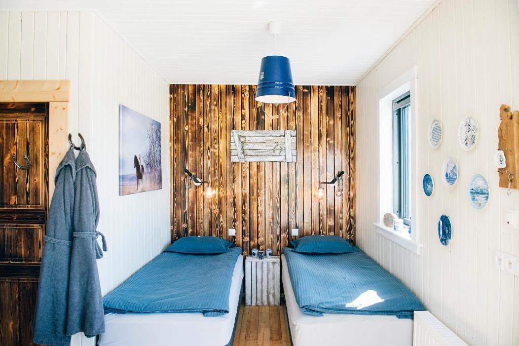 two twin beds in a room with wooden walls at Akurgerði Guesthouse 4 - Country Life Style in Ölfus