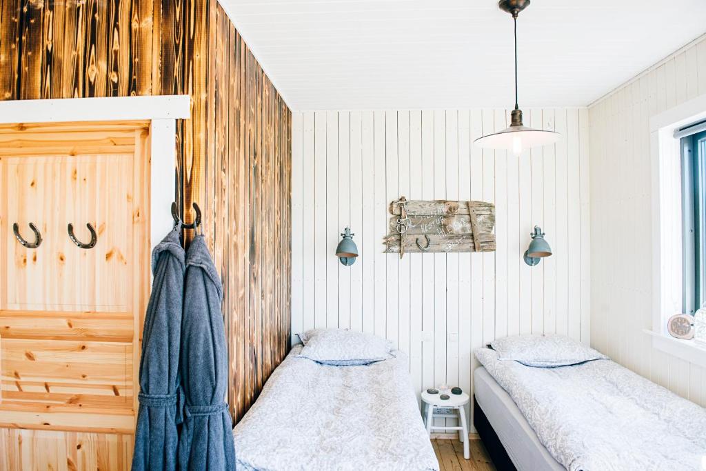 two beds in a bedroom with wooden walls at Akurgerði Guesthouse 6 - Country Life Style in Ölfus