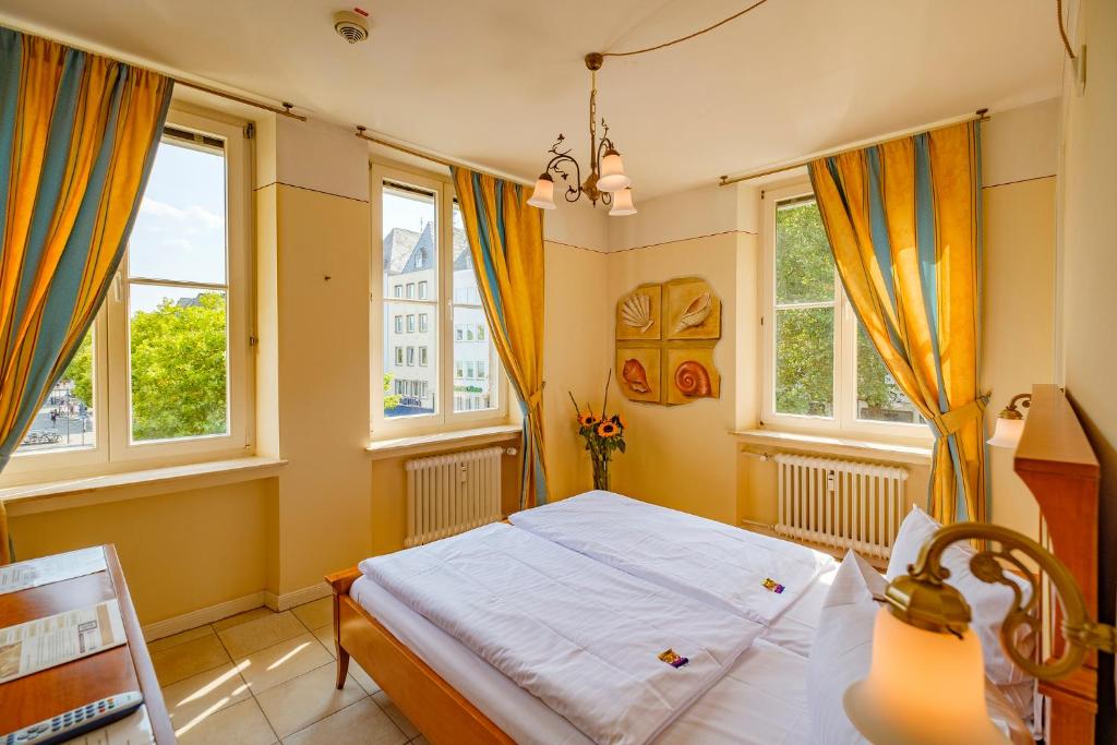 ein Schlafzimmer mit einem Bett und zwei Fenstern in der Unterkunft XII Apostel Albergo in Köln