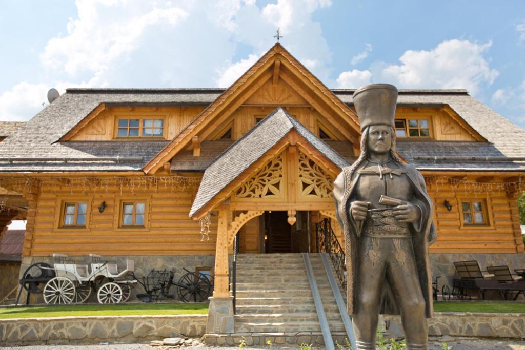 una estatua delante de una casa de troncos en Zbojnicky penzion, en Jasenica
