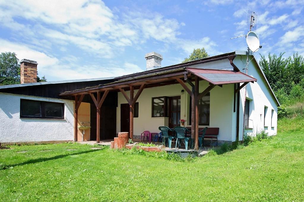 ein kleines weißes Haus mit einer Veranda und Stühlen in der Unterkunft Ubytování LENKA in Bělá pod Pradědem