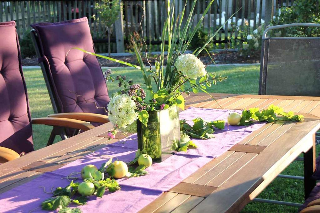 una mesa de madera con un jarrón de flores. en Ferienwohnung Landidyll en Saalburg