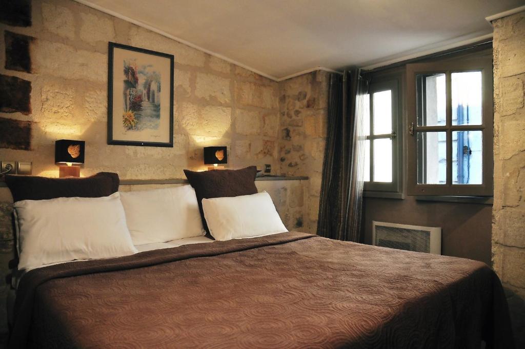 a bedroom with a large bed and two windows at Hôtel du Palais des Papes in Avignon