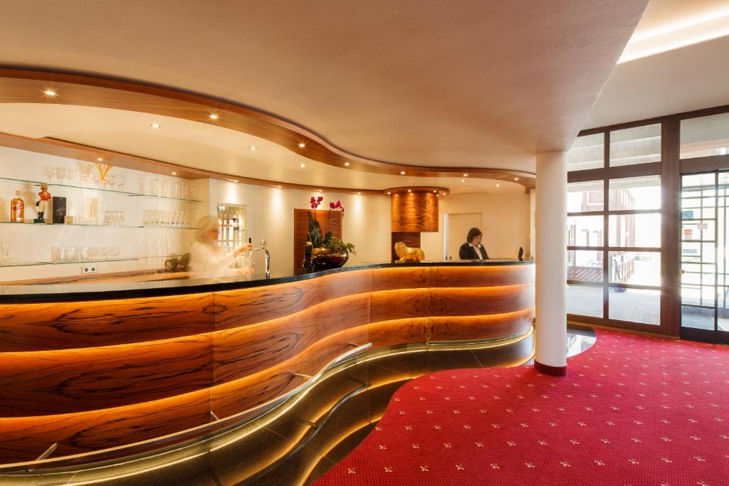 um átrio com um bar de madeira com tapete vermelho em INVITE Hotel Löwen Freiburg em Friburgo em Brisgóvia