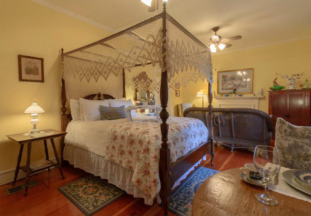 a bedroom with a canopy bed and a table at Magnolia Cottage Bed and Breakfast in Natchez