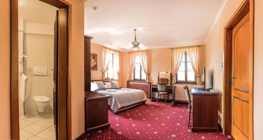1 dormitorio con cama, escritorio y baño en Hotel Buchlovice, en Buchlovice