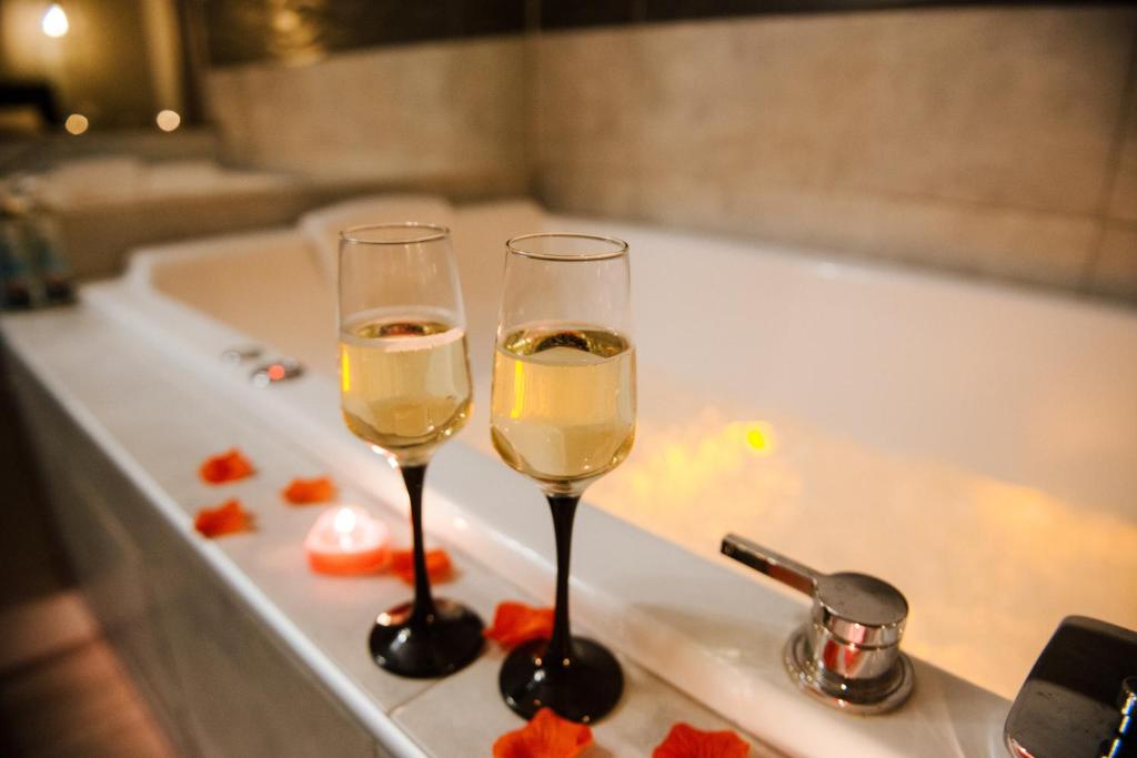 two glasses of wine sitting on a bath tub at La Suite Romantique avec Jacuzzi au Cœur de Perpignan in Perpignan