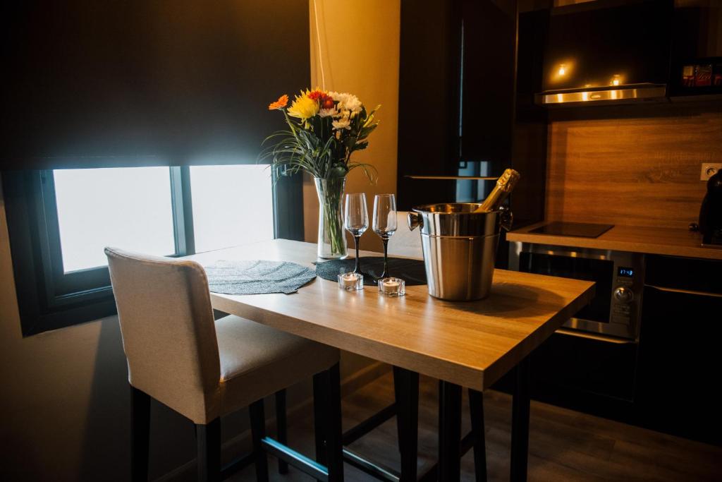 a kitchen table with a vase of flowers and wine glasses at La Suite Romantique avec Jacuzzi au Cœur de Perpignan in Perpignan