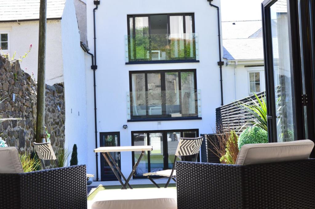 a white building with black windows and chairs on a patio at Pier39Portrush Adult Only in Portrush