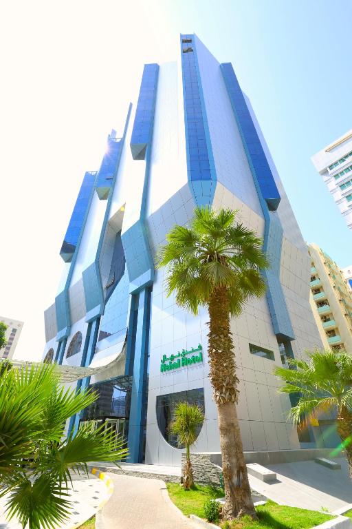 un bâtiment avec un palmier devant dans l'établissement Nehal Hotel, à Abu Dhabi