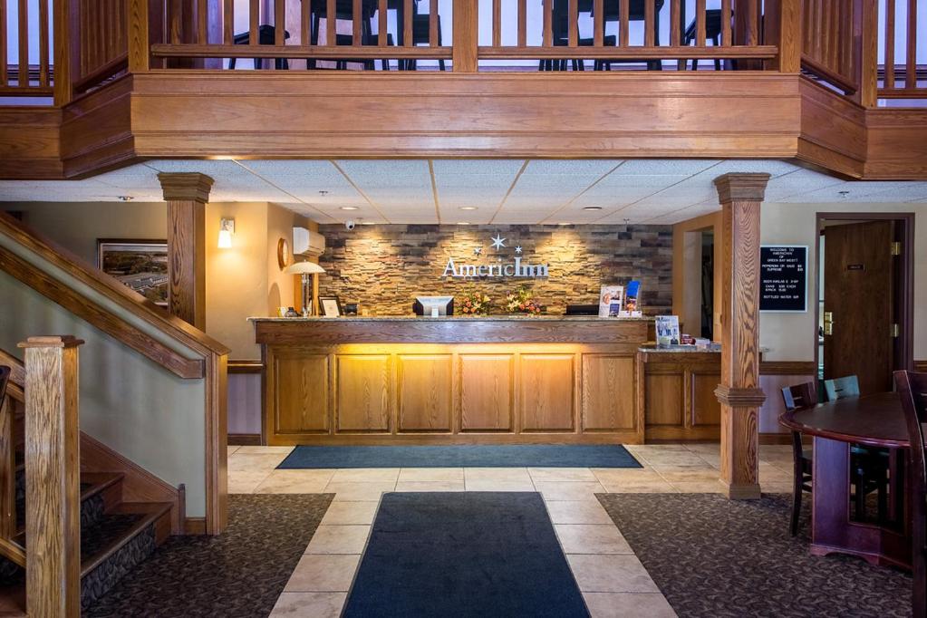 a restaurant with a bar in the middle of a room at AmericInn by Wyndham Green Bay West in Green Bay