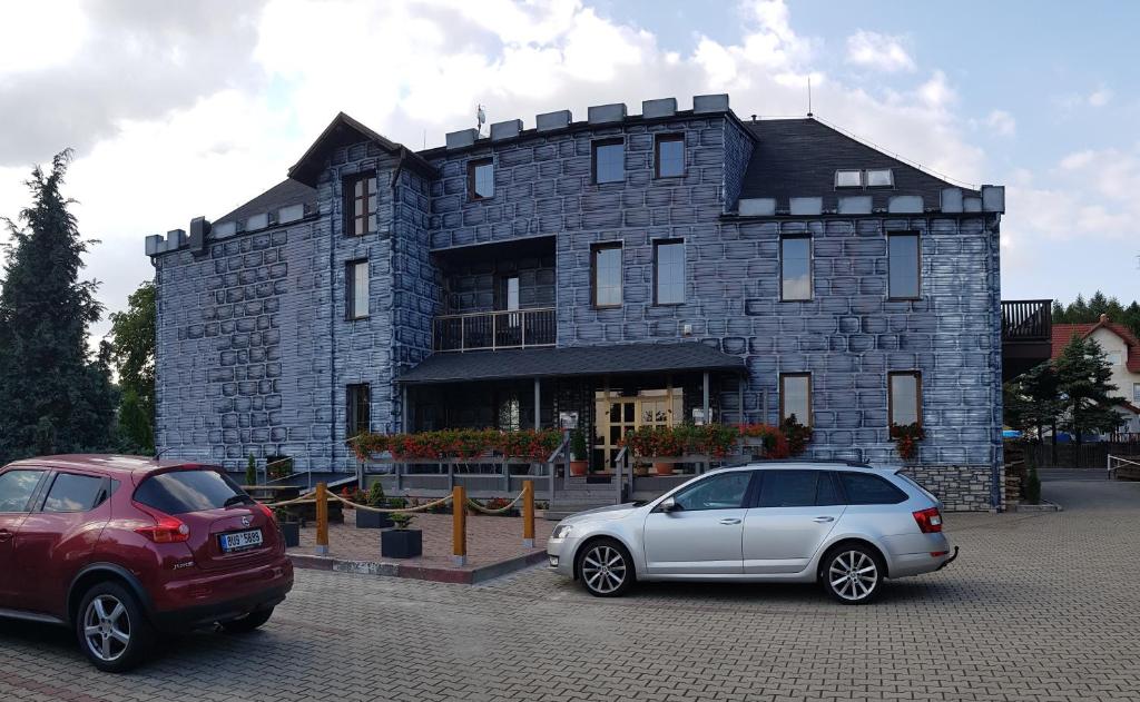 two cars parked in front of a stone building at Hotel Camelot in Tisá