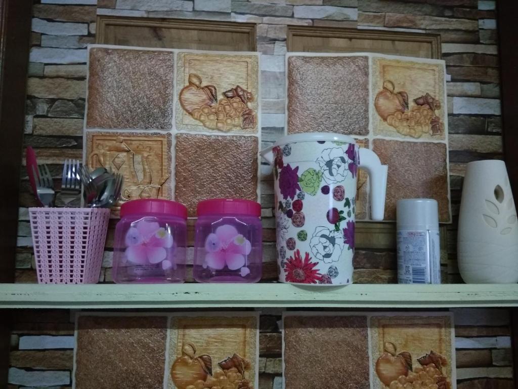 a shelf with cups and other items on it at Bonda Guesthouse II in Paka