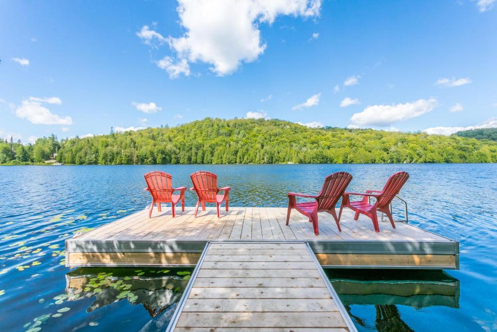 four chairs sitting on a dock on a lake at Le Grand Shack- Locations du Sommet in Saint Adolphe D'Howard