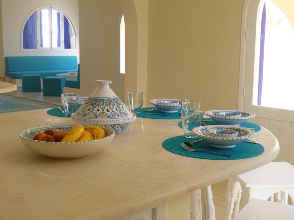 a table with bowls of fruit and plates on it at Dar A'Mina in Zarzis