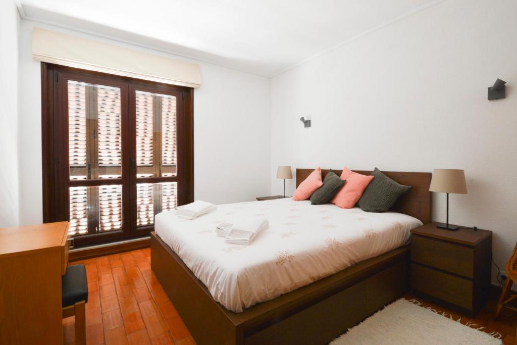 a bedroom with a large bed and a window at Sesimbra 99 - T2 Apartment in Sesimbra