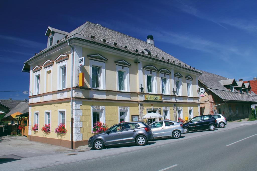 ein Gebäude mit Autos, die an der Straßenseite geparkt sind in der Unterkunft Guesthouse Osvald in Žirovnica