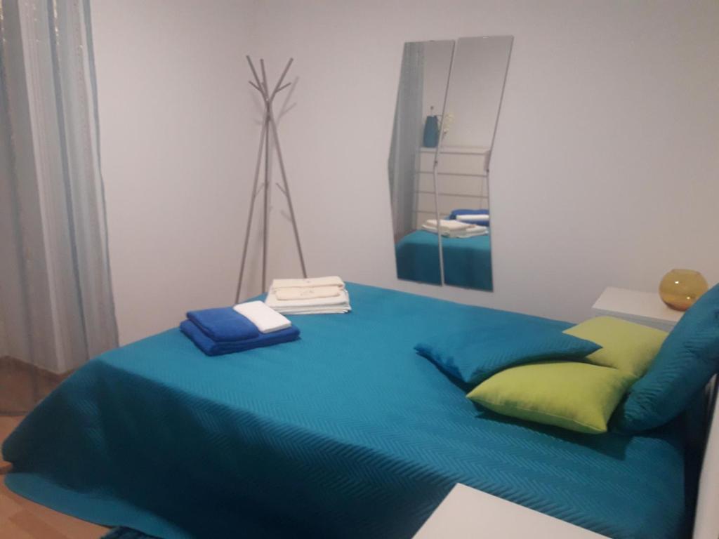 a bed with a blue blanket and a mirror at Casa Cantinho dos Pais in Paredes de Coura
